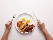 Руки по тарелке жареного завтрака — стоковое фото