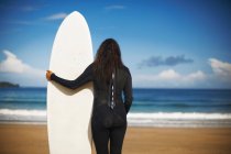Rear view of female surfer holding board on beach — Stock Photo