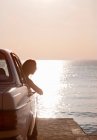 Woman with oldtimer by sea at the sunset — Stock Photo