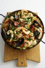 Paella in frying pan on wooden board — Stock Photo