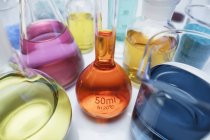Volumetric flask containing solution of potassium dichromate and other flasks of transition metal salts — Stock Photo