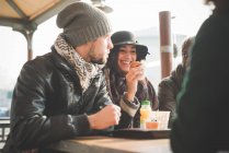 Quattro giovani amici adulti che chiacchierano e mangiano ciambelle al caffè marciapiede — Foto stock