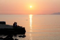 Coppia relax sul molo al tramonto — Foto stock