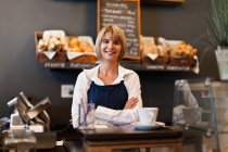 Усміхнена жінка працює в кафе, зосередьтеся на передньому плані — стокове фото