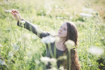 Junge Frau pflückt Wildblumen auf Feld — Stockfoto