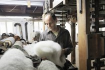 Рабочий смотрит на шерсть на шерстяной фабрике — стоковое фото