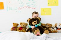 Junge umarmt Teddybär auf Bett — Stockfoto