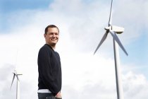 Усміхнений чоловік стоїть на вітроелектростанції — стокове фото