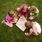 Elevated view of girls making kite on grass — Stock Photo