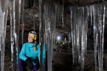 Hiker admiring icicles in cave — Stock Photo