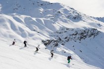 Лыжники катаются вместе на склоне — стоковое фото