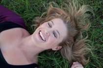 Улыбающаяся женщина лежит в траве — стоковое фото