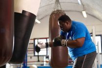 Boxeador con saco de boxeo en gimnasio - foto de stock