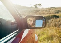 Girl looking in car mirror — Stock Photo