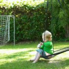 Baby girl sitting on swing in backyard — Stock Photo