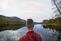 Hombre mirando al lago, Kesankijarvi, Laponia, Finlandia - foto de stock