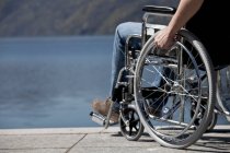 Vista cortada do homem em cadeira de rodas sentado à água — Fotografia de Stock