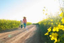 Mother and daughter walking on dirt road — Stock Photo