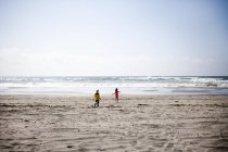 Menino e menina correndo para o mar — Fotografia de Stock