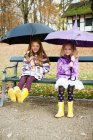Дівчата в дощових черевиках і парасольках в парку — стокове фото