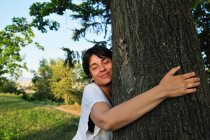 Frau umarmt Baum im Wald — Stockfoto