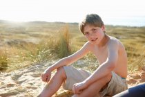 Niño sentado en la playa - foto de stock