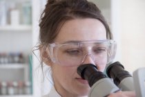Женщина-ученый смотрит в микроскоп — стоковое фото