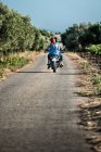 Rear view of mid adult couple riding motorcycle on rural road, Cagliari, Sardinia, Italy — Stock Photo