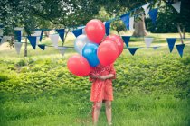 Menina segurando monte de balões ao ar livre — Fotografia de Stock