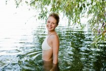 Donna sorridente guadare nel fiume — Foto stock