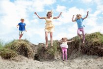 Mother with three children jumping off dunes, Wales, UK — Stock Photo