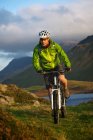 Ciclista de montaña en ladera cubierta de hierba - foto de stock