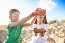 Dos chicas jugando con arena en la playa - foto de stock