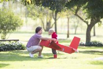 Padre agacharse a la preparación de juguete avión para hijo en el parque - foto de stock