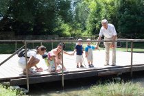 Familia examinando río en puente - foto de stock
