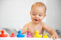 Мальчик играет с пластиковыми утками в ванной — стоковое фото