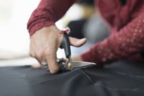 Seamstress hands using scissors to cut textile — Stock Photo