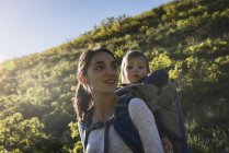 Madre che porta la giovane figlia sul retro, facendo escursioni lungo il Bonneville Shoreline Trail ai piedi del Wasatch Foothills sopra Salt Lake City, Utah, USA — Foto stock