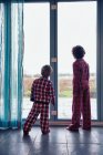 Мальчики в пижаме, выглядывающие в окно — стоковое фото