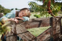 Menina pequena inclinada sobre a cerca ao ar livre — Fotografia de Stock
