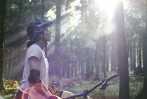 Mountainbikerin steht mit geschlossenen Augen im Sonnenstrahl, Wald von Dekan, Bristol, UK — Stockfoto