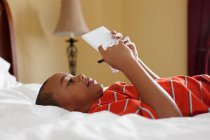 Мальчик играет в карманную видеоигру на кровати — стоковое фото