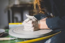 Vista lateral de jovens mulheres mãos moldando argila na roda de cerâmica — Fotografia de Stock
