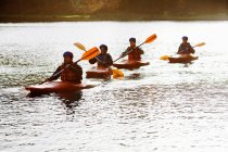 Kayakers remando juntos en un lago tranquilo - foto de stock