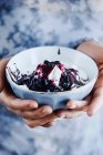Female hands holding bowl of ice cream with berry syrup — Stock Photo