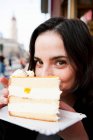 Молода жінка тримає тарілку з шматочком торта і посміхається — стокове фото