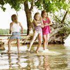 Улыбающиеся девушки, играющие в озере, внимание на переднем плане — стоковое фото