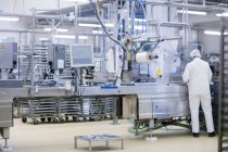 Visão traseira do trabalhador da fábrica que opera máquinas de produção de alimentos — Fotografia de Stock