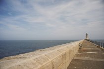 Harbour wall and lighthouse — Stock Photo