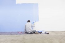 Rear view of man painting wall blue — Stock Photo